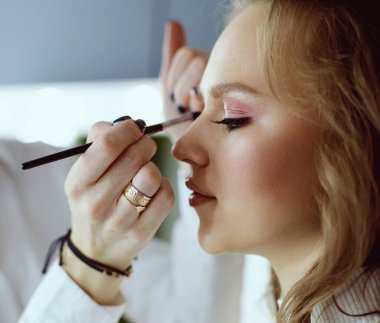 Güzel, genç bir model kadın makyaj yaptırıyor.
