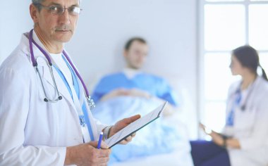 Doktor bir hastanın ve doktorun önünde klasörü tutuyor.