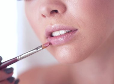 Genç bir kadının banyoya yüz pudrası sürerken fotoğrafı.