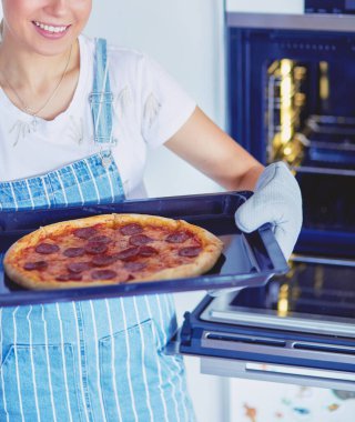 Mutlu genç bayan evde pizza pişiriyor.