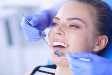 Dişçi muayenehanesinde diş muayenesi yapan ağzı açık genç bir kadın hasta..