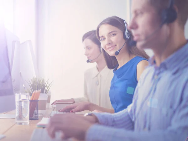 Lächelnde Callcenter-Mitarbeiter sitzen mit ihrem Headset in der Schlange — Stockfoto