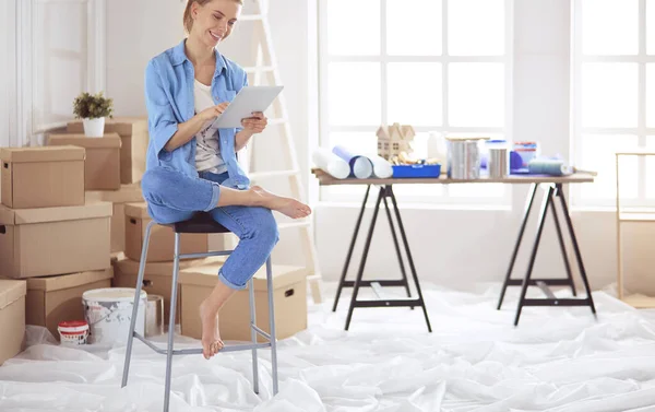Jonge vrouw zit thuis en koopt nieuwe meubels via internet met behulp van een tablet computer — Stockfoto