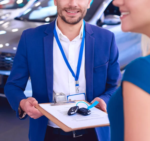 Vendedor de carro vende um carro ao cliente feliz na concessionária de carro e entrega as chaves — Fotografia de Stock