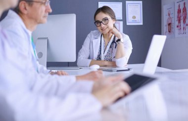 Ciddi bir tıbbi ekip parlak bir ofiste dizüstü bilgisayar kullanıyor.