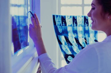 Genç, profesyonel kadın doktor hastaların röntgenlerini çekiyor.