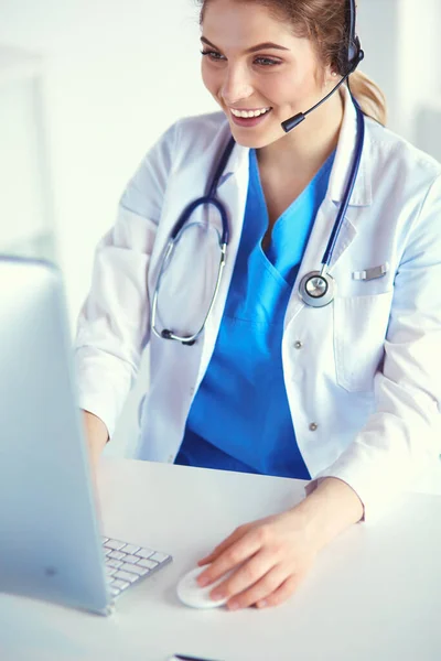 Médico con auriculares sentado detrás de un escritorio con portátil —  Fotos de Stock