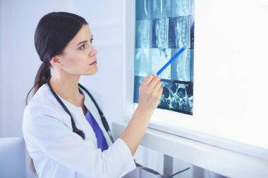 Stetoskop lu genç gülümseyen kadın doktor doktor ofisinde röntgeni işaret ediyor
