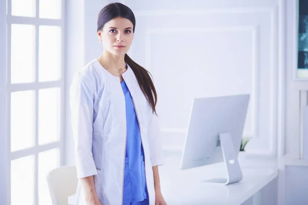 Porträtt av ung kvinna läkare i vit rock stående på sjukhus — Stockfoto