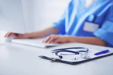 Kadın doktor oturuyor ve dizüstü bilgisayarda çalışıyor.