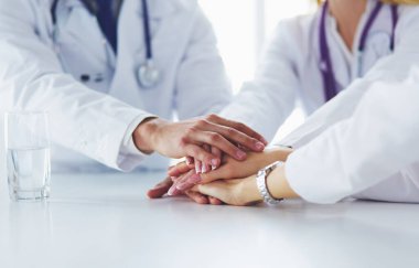 Doktorlar el ele tutuşup yakın çekim yapıyor.