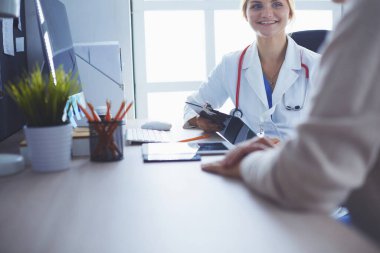 Bir doktor konuşuyor ve bir hastayı muayene ediyor.