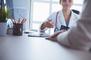 Kadın doktor hastaya danışmanlık yaparken başvuru formu tutuyor