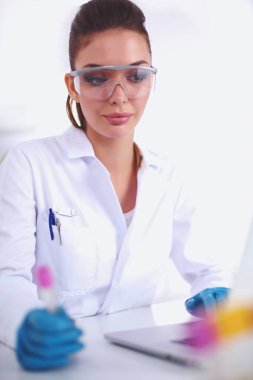 Kadın araştırmacının etrafı ilaç şişeleri ve mataralarla çevrili.