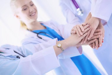 Doktorlar ve hemşireler tıbbi bir ekipte el ele tutuşuyorlar.