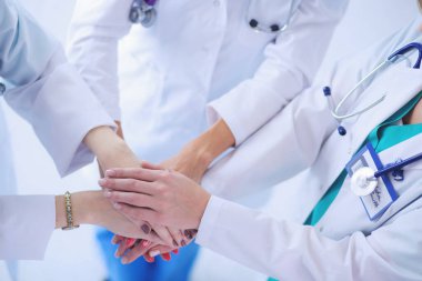 Doktorlar ve hemşireler tıbbi bir ekipte el ele tutuşuyorlar.