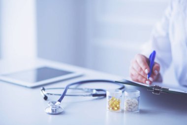 Steteskop cam masanın üzerinde duruyor. Yoğun bir doktor geçmişinde dizüstü bilgisayarı var. İlaç ya da eczane konsepti. Doktor çalışma masasında tıbbi aletler