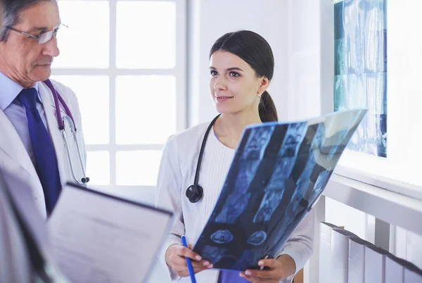 Mosolygó orvosok beszélgetnek a betegek diagnózisáról, miközben röntgenfelvételeket nézegetnek a kórházban. — Stock Fotó