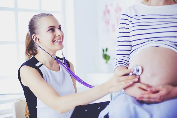 Mladá žena lékař se stetoskopem a tablet mluvit s těhotnou ženou v nemocnici. — Stock fotografie
