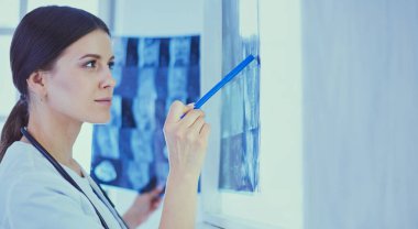 Stetoskop lu genç gülümseyen kadın doktor doktor ofisinde röntgeni işaret ediyor