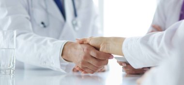 Doktor ofiste erkek bir hastayla el sıkışıyor.