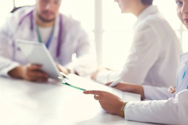 Ciddi bir tıbbi ekip parlak bir ofiste dizüstü bilgisayar kullanıyor.