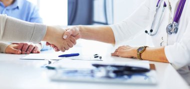Yaşlı bir çiftle el sıkışan kadın doktor.