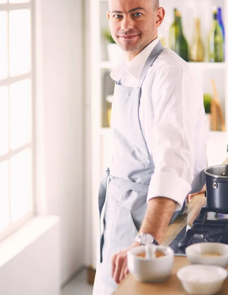 Handsome man is cooking on kitchen and smiling