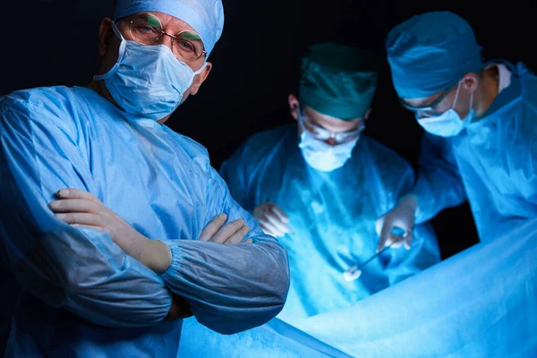 파란색으로 칠 해진 수술실에서 외과의들 이 일하고 있습니다. 수술을 수행하는 의료 팀 — 스톡 사진