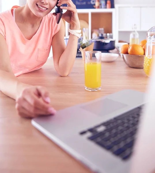 Ung kvinna i köket med bärbar dator ser recept, leende. Begreppet livsmedelsbloggare — Stockfoto