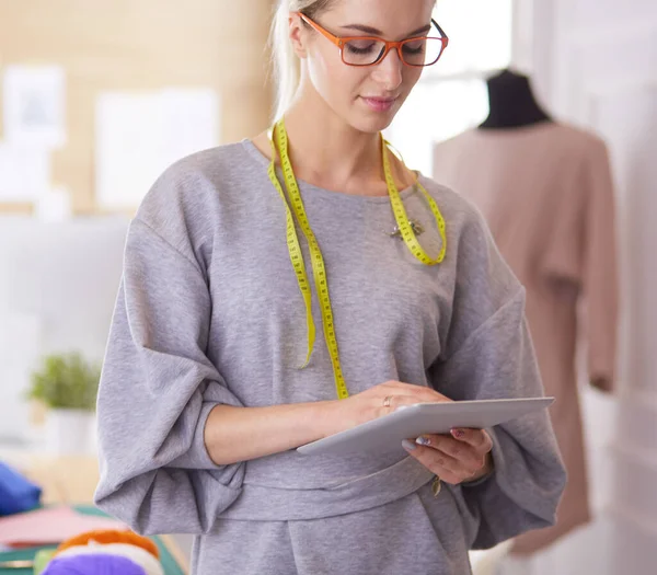 Bella giovane donna che lavora su tablet digitale e sorride mentre si siede al suo posto di lavoro — Foto Stock