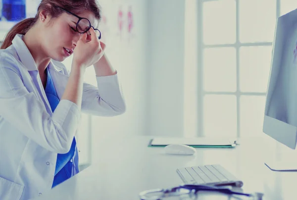 Porträtt av en ung kvinnlig läkare som lider av huvudvärk på jobbet — Stockfoto