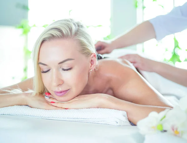 Молода жінка в спа-салоні, отримання кам'яного масажу — стокове фото