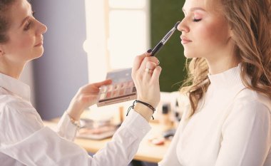 Güzel, genç bir model kadın makyaj yaptırıyor.