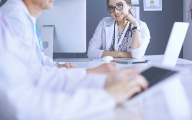 Ciddi bir tıbbi ekip parlak bir ofiste dizüstü bilgisayar kullanıyor.