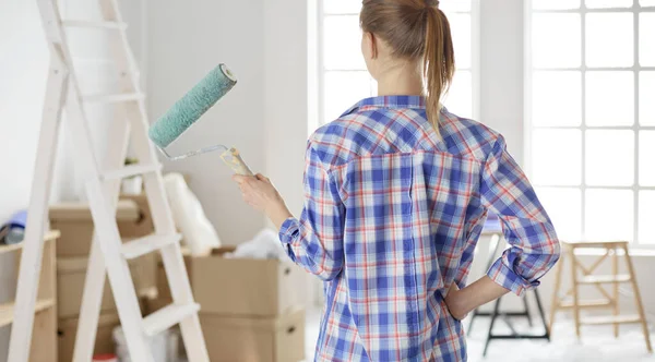 Ganska smilling kvinna målning interiör vägg i hemmet med färg roller — Stockfoto