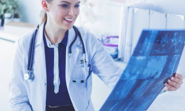 Genç ve çekici bayan doktor röntgen görüntülerine bakıyor.