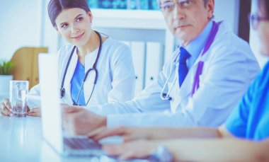 Parlak bir hastane odasında meslektaşlarıyla çalışan gülümseyen bir doktor.