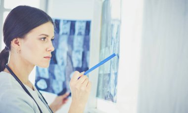 Stetoskop lu genç gülümseyen kadın doktor doktor ofisinde röntgeni işaret ediyor