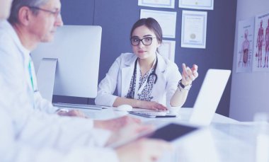 Ciddi bir tıbbi ekip parlak bir ofiste dizüstü bilgisayar kullanıyor.