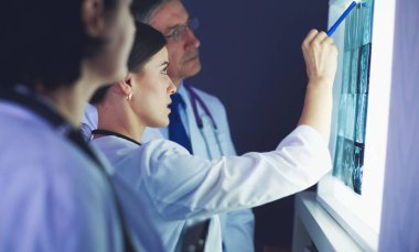 Bir grup doktor bir klinikte röntgenleri inceliyor, teşhis koymayı düşünüyorlar.