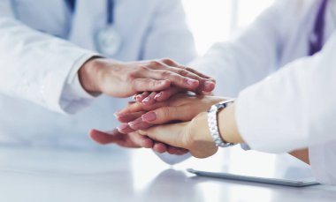 Doktorlar el ele tutuşup yakın çekim yapıyor.