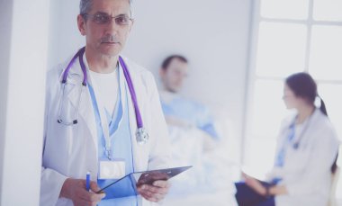 Doktor bir hastanın ve doktorun önünde klasörü tutuyor.