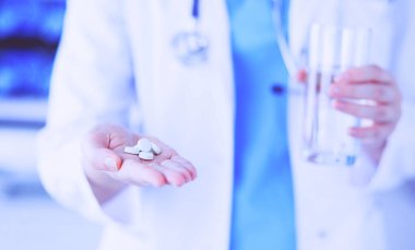 Doktorların ellerinde haplar ve bir bardak su tutarken yakın plan çekimleri..