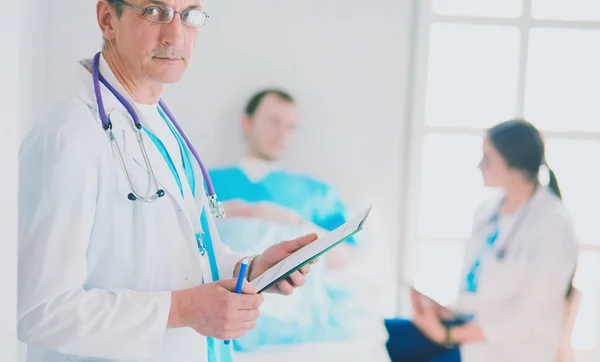 Läkaren håller mapp framför en patient och en läkare — Stockfoto