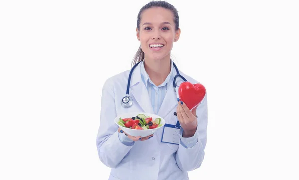 Retrato de una hermosa doctora sosteniendo un plato con vegetales frescos y corazón rojo. Mujeres doctores . —  Fotos de Stock