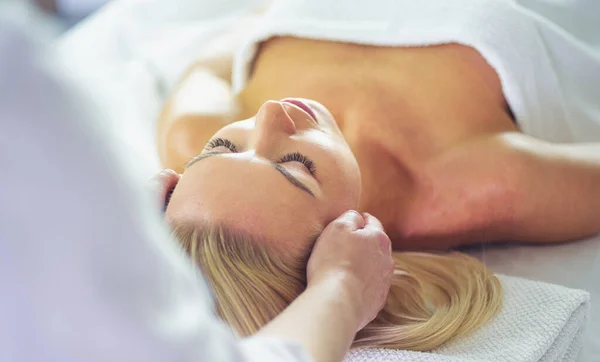 Schöne Frau tut Gesichtsmassage in einem Wellness-Salon Stockbild