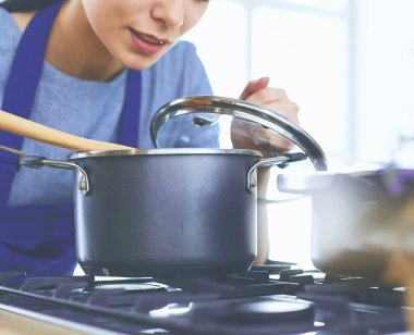 Mutfakta ahşap kaşıkla yemek pişiren kadın