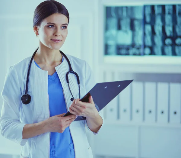 Giovane sorridente medico femminile con stetoscopio in possesso di una cartella presso lo studio medico — Foto Stock