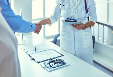 Yaşlı bir çiftle el sıkışan kadın doktor.